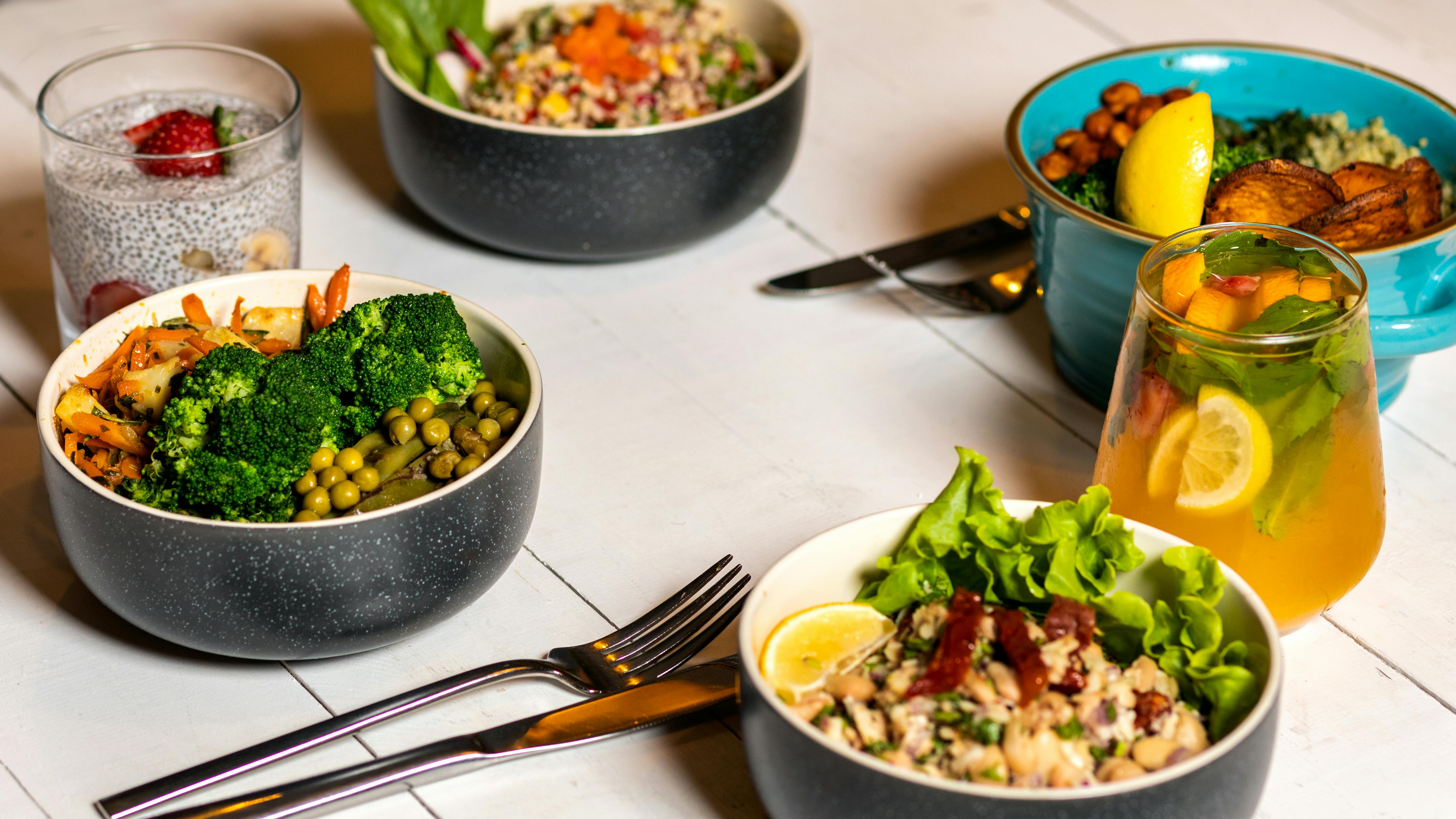 A vibrant assortment of healthy bowls and drinks showcasing fresh ingredients like broccoli and citrus.