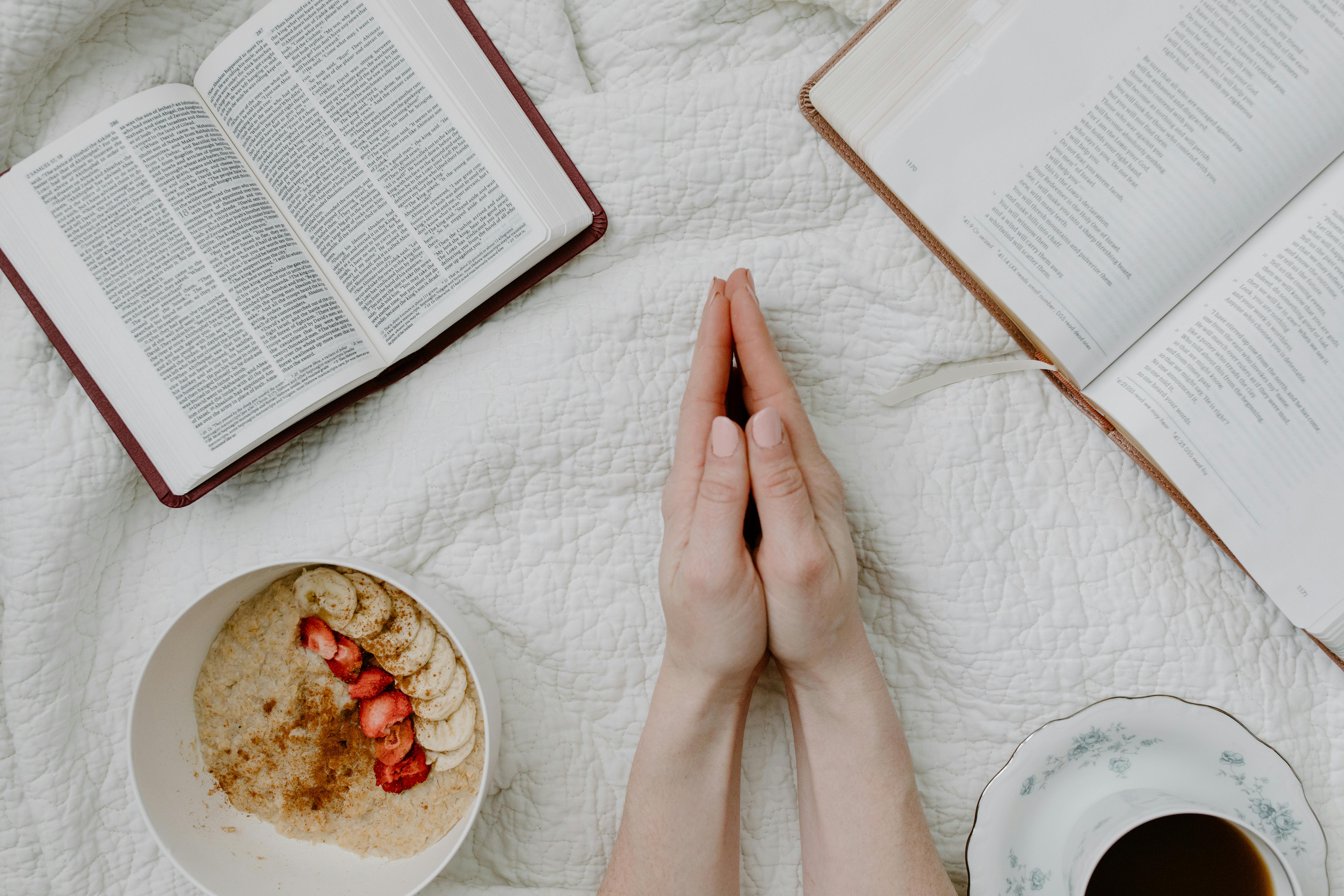 A serene morning scene with a person praying, an open Bible, oatmeal, and coffee.